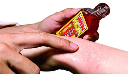 Applying red flower oil on hands